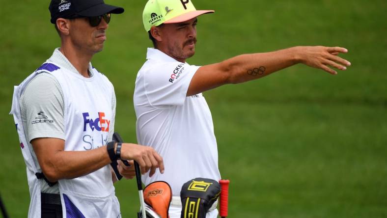 Jul 30, 2020; Memphis, Tennessee, USA; Rickie Fowler and his caddie Joe Skovron look down the 10th fairway during the first round of the WGC - FedEx St. Jude Invitational golf tournament at TPC Southwind. Mandatory Credit: Christopher Hanewinckel-USA TODAY Sports