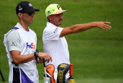 Jul 30, 2020; Memphis, Tennessee, USA; Rickie Fowler and his caddie Joe Skovron look down the 10th fairway during the first round of the WGC - FedEx St. Jude Invitational golf tournament at TPC Southwind. Mandatory Credit: Christopher Hanewinckel-USA TODAY Sports