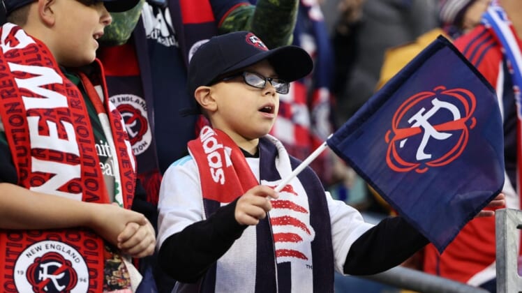 Nov 7, 2021; Foxborough, Massachusetts, USA; A young New England Revolution fan waves a flag with the team   s new logo for the 2022-23 season during the first half of the game between the New England Revolution and the Inter Miami at Gillette Stadium. Mandatory Credit: Winslow Townson-USA TODAY Sports