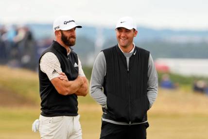 Jul 14, 2022; St. Andrews, SCT; Dustin Johnson (left) talks with Scottie Scheffler during a delay on the 14th hole during the first round of the 150th Open Championship golf tournament at St. Andrews Old Course. Mandatory Credit: Rob Schumacher-USA TODAY Sports