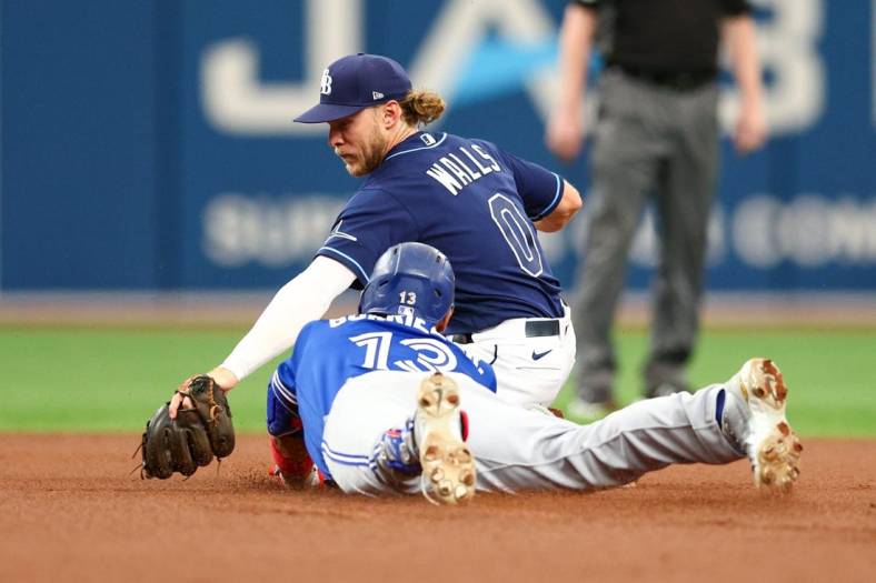 Aug 3, 2022; St. Petersburg, Florida, USA;  Toronto Blue Jays left fielder Lourdes Gurriel Jr. (13) runs out a double while Tampa Bay Rays shortstop Taylor Walls (0) applies a tag in the first inning at Tropicana Field. Mandatory Credit: Nathan Ray Seebeck-USA TODAY Sports