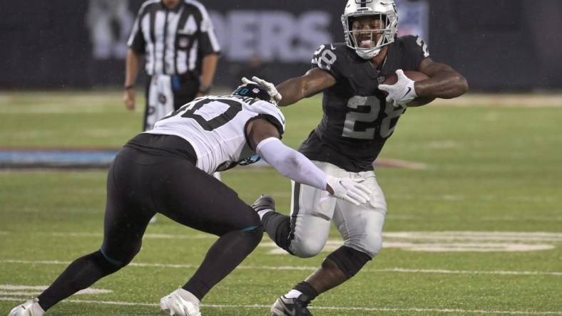 Aug 4, 2022; Canton, Ohio, USA; Las Vegas Raiders running back Josh Jacobs (28) runs against Jacksonville Jaguars linebacker Shaquille Quarterman (50) in the first quarter at Tom Benson Hall of Fame Stadium. Mandatory Credit: Ken Blaze-USA TODAY Sports