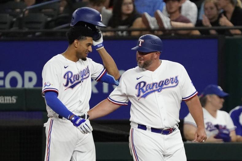 Aug 4, 2022; Arlington, Texas, USA; Texas Rangers left fielder Bubba Thompson (65) is congratulated by first base coach Corey Ragsdale (64) after bunting for his first MLB hit during the seventh inning against the Chicago White Sox at Globe Life Field. Mandatory Credit: Raymond Carlin III-USA TODAY Sports