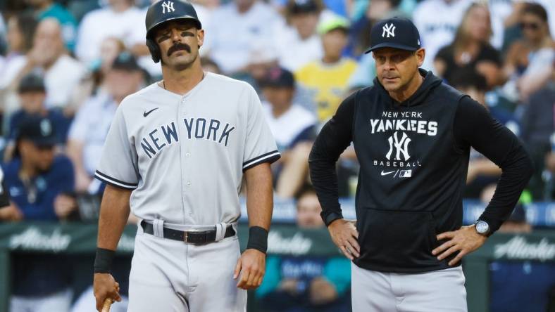 Aug 8, 2022; Seattle, Washington, USA; New York Yankees designated hitter Matt Carpenter (left) reacts while manager Aaron Boone (right) watches after a foul ball struck his foot during the first inning against the Seattle Mariners at T-Mobile Park. Mandatory Credit: Joe Nicholson-USA TODAY Sports