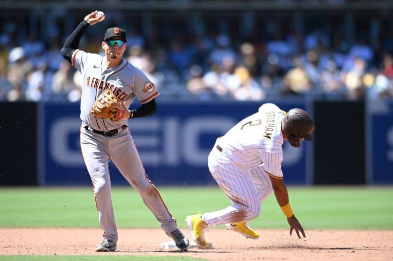 Aug 10, 2022; San Diego, California, USA; San Francisco Giants second baseman Wilmer Flores (left) throws to first base late after forcing out San Diego Padres center fielder Trent Grisham (2) at second base during the third inning at Petco Park. Mandatory Credit: Orlando Ramirez-USA TODAY Sports