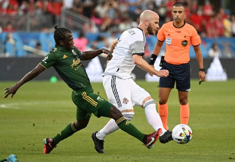 Aug 13, 2022; Toronto, Ontario, CAN;  Toronto FC midfielder Michael Bradley (4) passes the ball away from Portland Timbers midfielder Diego Chara (21) in the first half at BMO Field. Mandatory Credit: Dan Hamilton-USA TODAY Sports