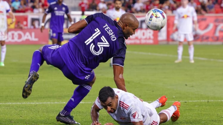 Aug 13, 2022; Harrison, New Jersey, USA; Orlando City SC forward Tesho Akindele (13) heads the ball over New York Red Bulls midfielder Cristian Casseres Jr (23) during the second half at Red Bull Arena. Mandatory Credit: Vincent Carchietta-USA TODAY Sports