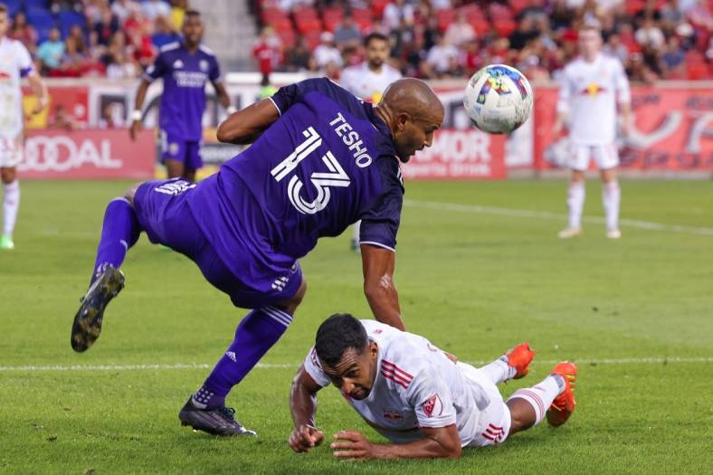 Aug 13, 2022; Harrison, New Jersey, USA; Orlando City SC forward Tesho Akindele (13) heads the ball over New York Red Bulls midfielder Cristian Casseres Jr (23) during the second half at Red Bull Arena. Mandatory Credit: Vincent Carchietta-USA TODAY Sports