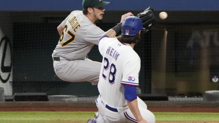 Aug 18, 2022; Arlington, Texas, USA; Texas Rangers catcher Jonah Heim (28) slides as he is tagged out at home by Oakland Athletics starting pitcher Zach Logue (67) during the second inning at Globe Life Field. Mandatory Credit: Jim Cowsert-USA TODAY Sports
