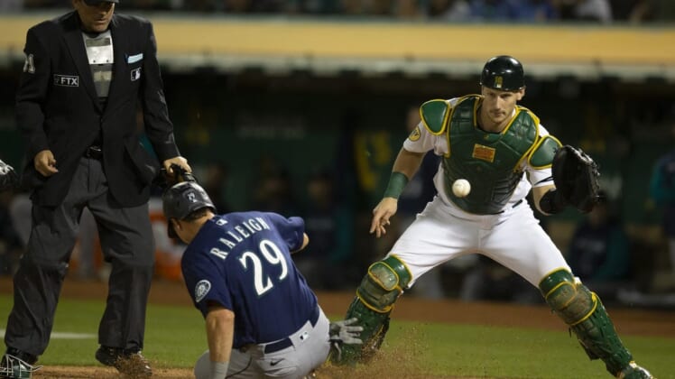 Aug 19, 2022; Oakland, California, USA; Seattle Mariners catcher Cal Raleigh (29) slides safely home ahead of the relay to Oakland Athletics catcher Sean Murphy (12) during the eighth inning at RingCentral Coliseum. Mandatory Credit: D. Ross Cameron-USA TODAY Sports