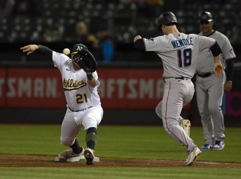 Aug 23, 2022; Oakland, California, USA; Oakland Athletics first baseman Stephen Vogt (21) takes the throw at first to force out Miami Marlins third baseman Joey Wendle (18) during the sixth inning at RingCentral Coliseum. Mandatory Credit: D. Ross Cameron-USA TODAY Sports