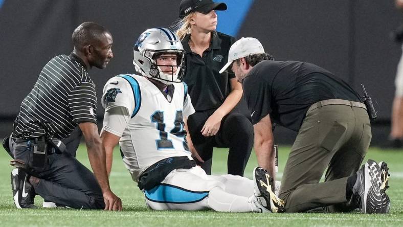 Aug 26, 2022; Charlotte, North Carolina, USA; Trainers attend to Carolina Panthers quarterback Sam Darnold (14) during the second half against the Buffalo Bills at Bank of America Stadium. Mandatory Credit: Jim Dedmon-USA TODAY Sports