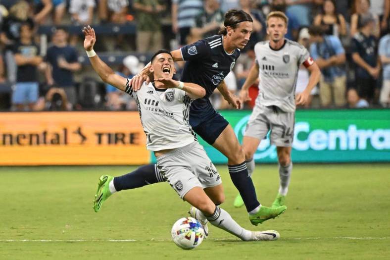 Aug 27, 2022; Kansas City, Kansas, USA; San Jose Earthquakes forward Cristian Espinoza (10) gets pulled down from behind by Sporting Kansas City defender Ben Sweat (2)during the first half at Children's Mercy Park. Mandatory Credit: Peter Aiken-USA TODAY Sports
