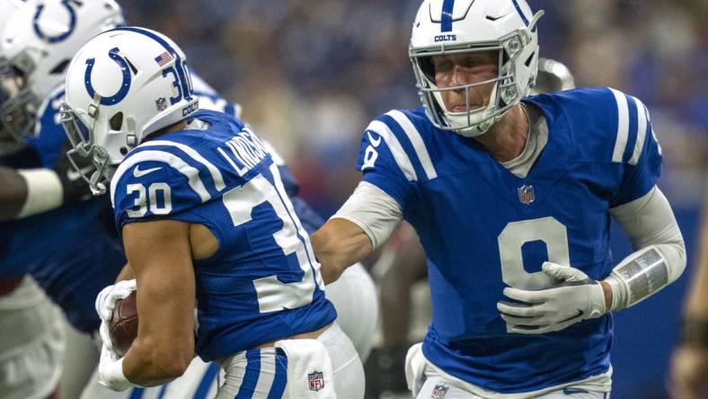 Aug 27, 2022; Indianapolis, Indiana, USA; Indianapolis Colts quarterback Nick Foles (9) hands off to running back Phillip Lindsay (30) against the Tampa Bay Buccaneers during a preseason game at Lucas Oil Stadium. Mandatory Credit: Robert Scheer-USA TODAY Sports