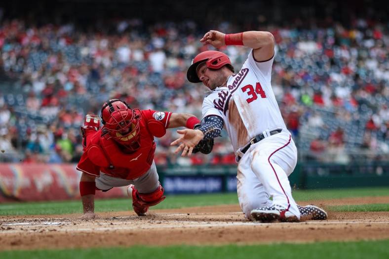 Aug 28, 2022; Washington, District of Columbia, USA; Washington Nationals first baseman Luke Voit (34) is tagged out at home by Cincinnati Reds catcher Austin Romine (28) during the fourth inning at Nationals Park. Mandatory Credit: Scott Taetsch-USA TODAY Sports