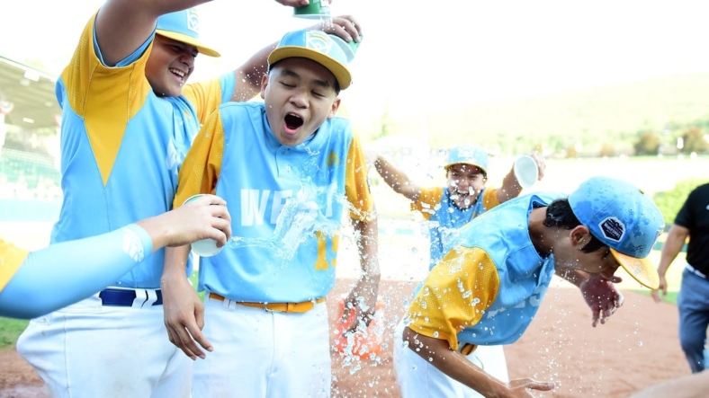 Aug 28, 2022; Williamsport, PA, USA; West Region shortstop Kekoa Payanal (15) and outfielder Kama Angell (14) get doused with gatorade by first baseman Esaiah Wong (20) and third baseman Daly Watson (12) after beating the Caribbean Region 13-3 at Lamade Stadium. Mandatory Credit: Evan Habeeb-USA TODAY Sports