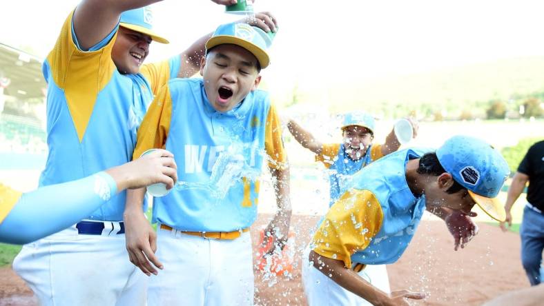 Aug 28, 2022; Williamsport, PA, USA; West Region shortstop Kekoa Payanal (15) and outfielder Kama Angell (14) get doused with gatorade by first baseman Esaiah Wong (20) and third baseman Daly Watson (12) after beating the Caribbean Region 13-3 at Lamade Stadium. Mandatory Credit: Evan Habeeb-USA TODAY Sports