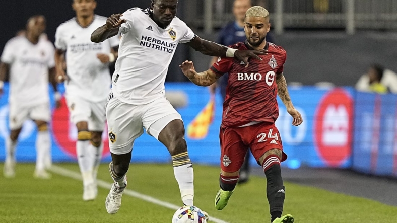 Aug 31, 2022; Toronto, Ontario, CAN; LA Galaxy defender Sega Coulibaly (4) battles for the ball with Toronto FC midfielder Lorenzo Insigne (24) during the first half at BMO Field. Mandatory Credit: John E. Sokolowski-USA TODAY Sports