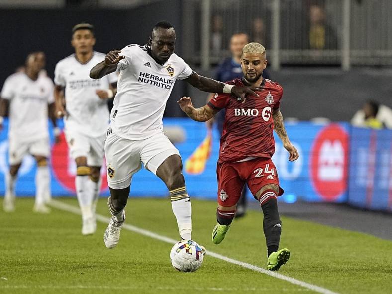 Aug 31, 2022; Toronto, Ontario, CAN; LA Galaxy defender Sega Coulibaly (4) battles for the ball with Toronto FC midfielder Lorenzo Insigne (24) during the first half at BMO Field. Mandatory Credit: John E. Sokolowski-USA TODAY Sports