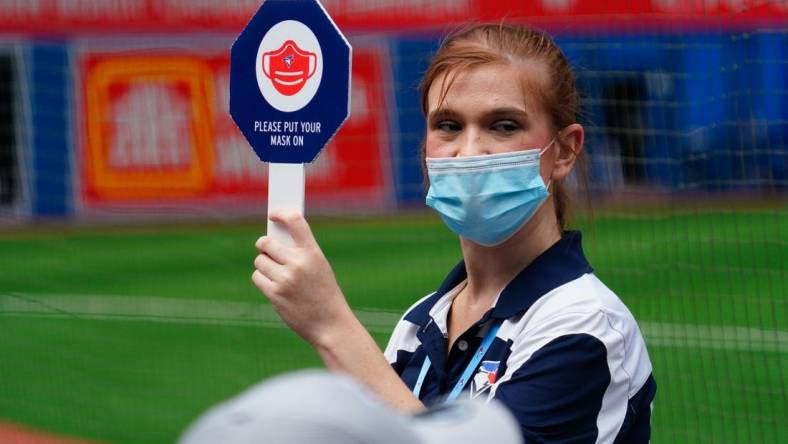 Aug 22, 2021; Toronto, Ontario, CAN; A Toronto Blue Jays stadium attendant holds up a sign reminding fans to wear their masks during a game against the Detroit Tigers at Rogers Centre. Mandatory Credit: John E. Sokolowski-USA TODAY Sports