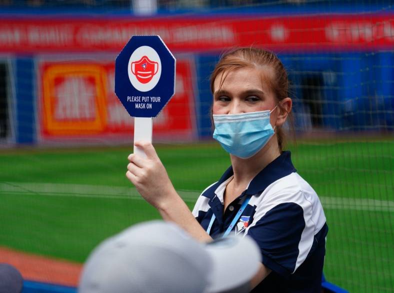 Aug 22, 2021; Toronto, Ontario, CAN; A Toronto Blue Jays stadium attendant holds up a sign reminding fans to wear their masks during a game against the Detroit Tigers at Rogers Centre. Mandatory Credit: John E. Sokolowski-USA TODAY Sports