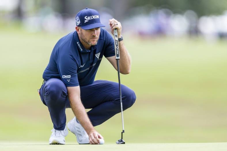 Jul 31, 2022; Detroit, Michigan, USA; Taylor Pendrith places his ball on the green on the par 4 first hole during the final round of the Rocket Mortgage Classic golf tournament. Mandatory Credit: Raj Mehta-USA TODAY Sports
