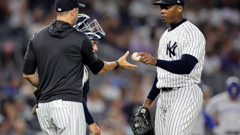 Aug 19, 2022; Bronx, New York, USA; New York Yankees relief pitcher Aroldis Chapman (54) hands the ball to manager Aaron Boone (17) after being taken out of the game against the Toronto Blue Jays during the ninth inning at Yankee Stadium. Mandatory Credit: Brad Penner-USA TODAY Sports