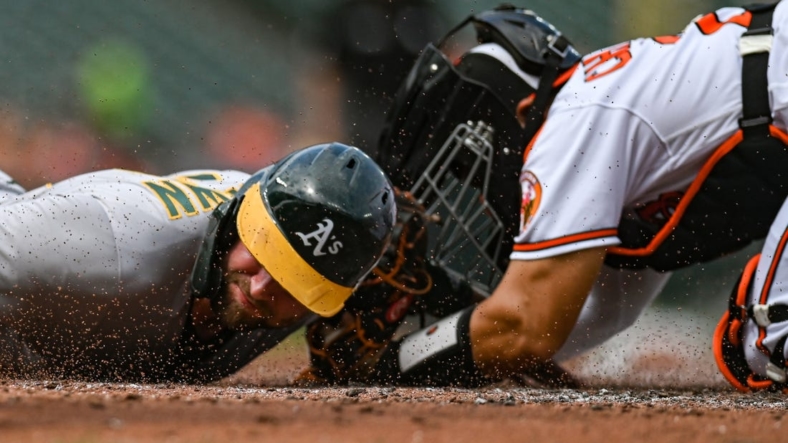 Sep 4, 2022; Baltimore, Maryland, USA;  Oakland Athletics first baseman Seth Brown (15) slides past Baltimore Orioles catcher Robinson Chirinos (23) to score during the second inning at Oriole Park at Camden Yards. Mandatory Credit: Tommy Gilligan-USA TODAY Sports