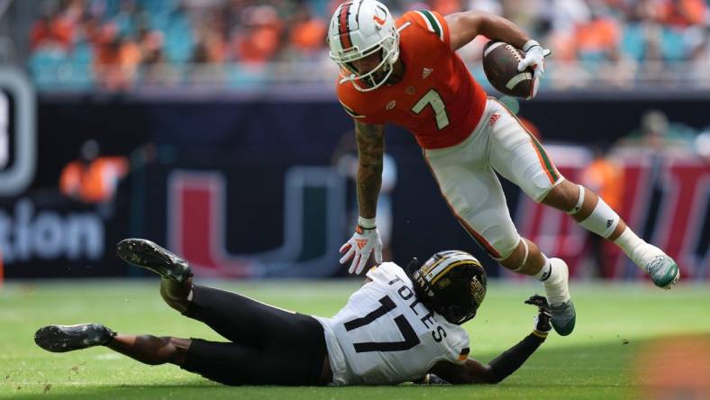 Sep 10, 2022; Miami Gardens, Florida, USA; Miami Hurricanes wide receiver Xavier Restrepo (7) leaps away from the tackle attempt of Southern Miss Golden Eagles defensive back Brendan Toles (17) during the second half at Hard Rock Stadium. Mandatory Credit: Jasen Vinlove-USA TODAY Sports