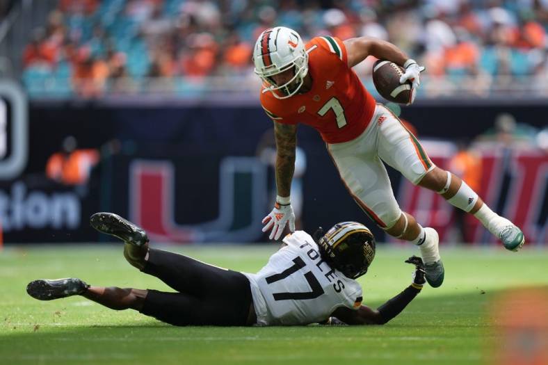 Sep 10, 2022; Miami Gardens, Florida, USA; Miami Hurricanes wide receiver Xavier Restrepo (7) leaps away from the tackle attempt of Southern Miss Golden Eagles defensive back Brendan Toles (17) during the second half at Hard Rock Stadium. Mandatory Credit: Jasen Vinlove-USA TODAY Sports