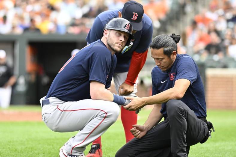 Sep 10, 2022; Baltimore, Maryland, USA;  Boston Red Sox second baseman Trevor Story (10) is checked by the team trainer after being hit by a pitch during the first inning against the Baltimore Orioles at Oriole Park at Camden Yards. Mandatory Credit: James A. Pittman-USA TODAY Sports