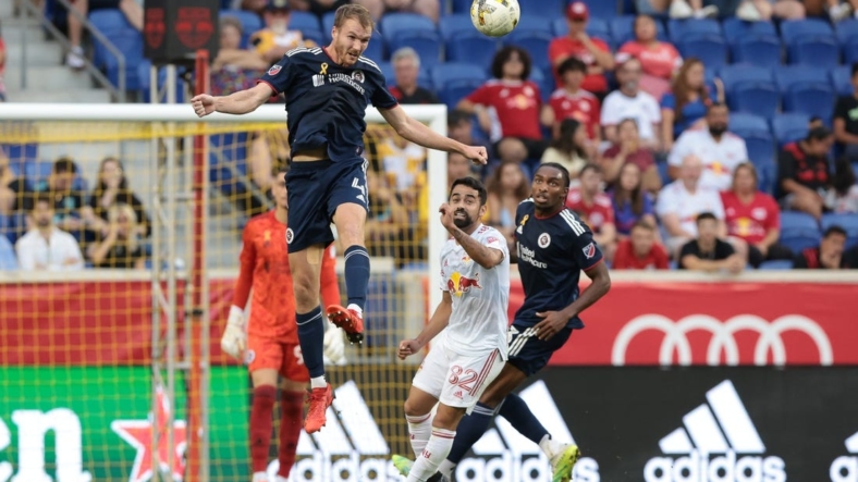 Sep 10, 2022; Harrison, New Jersey, USA; New England Revolution defender Henry Kessler (4) heads the ball away from New York Red Bulls midfielder Luquinhas (82) during the first half at Red Bull Arena. Mandatory Credit: Vincent Carchietta-USA TODAY Sports