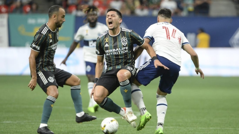 Sep 14, 2022; Vancouver, British Columbia, CAN;  Vancouver Whitecaps FC defender Luis Martins (14) collides with LA Galaxy midfielder Marco Delgado (8) during the first half at BC Place. Mandatory Credit: Anne-Marie Sorvin-USA TODAY Sports