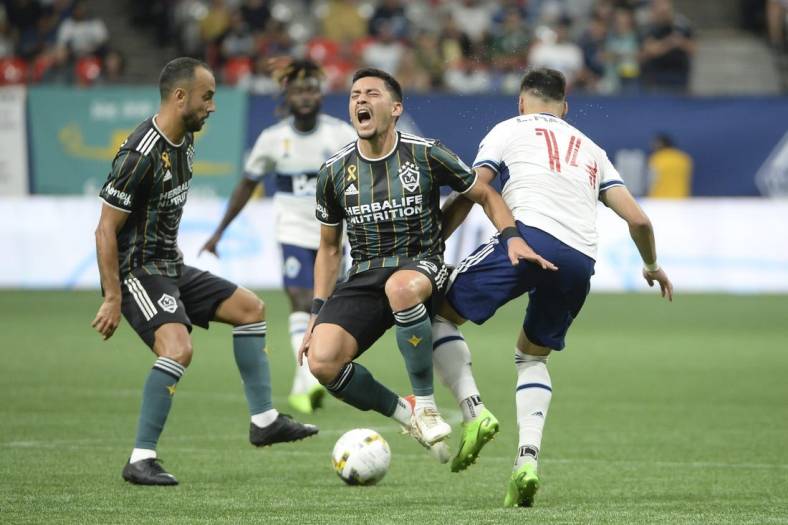 Sep 14, 2022; Vancouver, British Columbia, CAN;  Vancouver Whitecaps FC defender Luis Martins (14) collides with LA Galaxy midfielder Marco Delgado (8) during the first half at BC Place. Mandatory Credit: Anne-Marie Sorvin-USA TODAY Sports