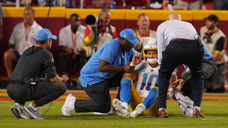 Sep 15, 2022; Kansas City, Missouri, USA; Los Angeles Chargers quarterback Justin Herbert (10) is looked at by team trainers after being hit by Kansas City Chiefs defensive end Mike Danna (51) during the second half at GEHA Field at Arrowhead Stadium. Mandatory Credit: Jay Biggerstaff-USA TODAY Sports