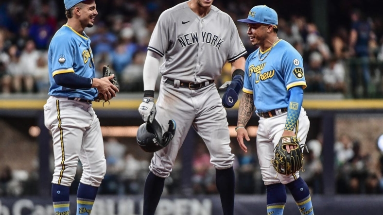 Sep 16, 2022; Milwaukee, Wisconsin, USA; New York Yankees center fielder Aaron Judge (99) talks to Milwaukee Brewers shortstop Willy Adames (27) and second baseman Kolten Wong (16) during a pause in the game in the second inning at American Family Field. Mandatory Credit: Benny Sieu-USA TODAY Sports