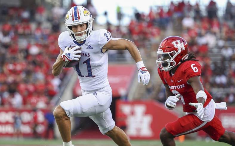 Sep 17, 2022; Houston, Texas, USA; Kansas Jayhawks wide receiver Luke Grimm (11) runs with the ball and scores a touchdown as Houston Cougars defensive back Jayce Rogers (6) defends during the second quarter at TDECU Stadium. Mandatory Credit: Troy Taormina-USA TODAY Sports