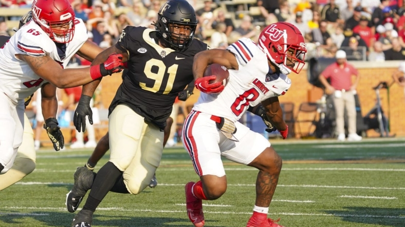 Sep 17, 2022; Winston-Salem, North Carolina, USA;  Liberty Flames running back Dae Dae Hunter (0) runs with the ball past Wake Forest Demon Deacons defensive lineman Kevin Pointer (91) during the first half at Truist Field. Mandatory Credit: James Guillory-USA TODAY Sports