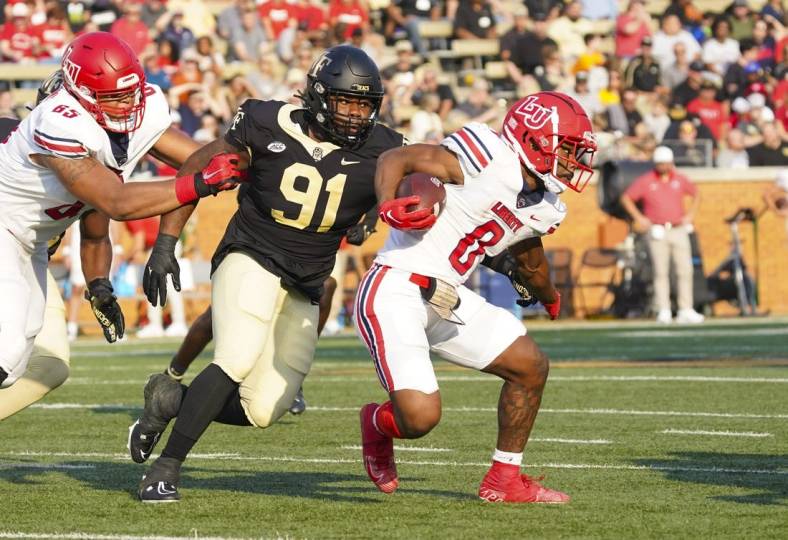 Sep 17, 2022; Winston-Salem, North Carolina, USA;  Liberty Flames running back Dae Dae Hunter (0) runs with the ball past Wake Forest Demon Deacons defensive lineman Kevin Pointer (91) during the first half at Truist Field. Mandatory Credit: James Guillory-USA TODAY Sports