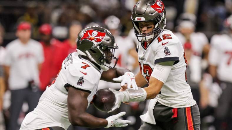 Sep 18, 2022; New Orleans, Louisiana, USA;  Tampa Bay Buccaneers quarterback Tom Brady (12) hands the ball off to running back Leonard Fournette (7) against the New Orleans Saints during the first half at Caesars Superdome. Mandatory Credit: Stephen Lew-USA TODAY Sports