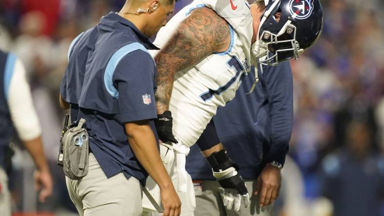 Sep 19, 2022; Orchard Park, New York, USA; Tennessee Titans offensive tackle Taylor Lewan (77) is helped off the field during the first quarter against the Buffalo Bills at Highmark Stadium. Mandatory Credit: George Walker IV -USA TODAY Sports