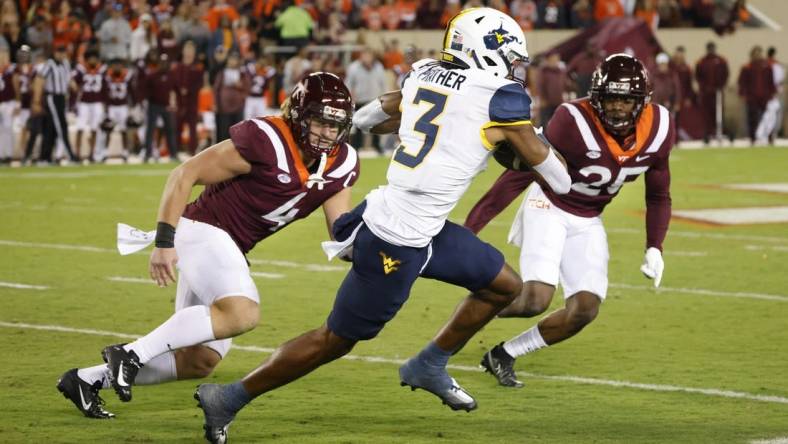 Sep 22, 2022; Blacksburg, Virginia, USA; West Virginia Mountaineers wide receiver Kaden Prather (3) runs the ball between Virginia Tech Hokies linebacker Dax Hollifield (4) and defensive back Chamarri Conner (25) at Lane Stadium. Mandatory Credit: Reinhold Matay-USA TODAY Sports