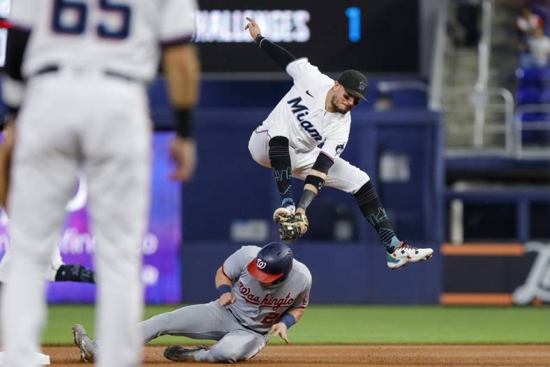 Sep 25, 2022; Miami, Florida, USA; Washington Nationals right fielder Lane Thomas (28) steals second base as Miami Marlins shortstop Miguel Rojas (11) jumps and attempts to tag him out during the first inning at loanDepot Park. Mandatory Credit: Sam Navarro-USA TODAY Sports