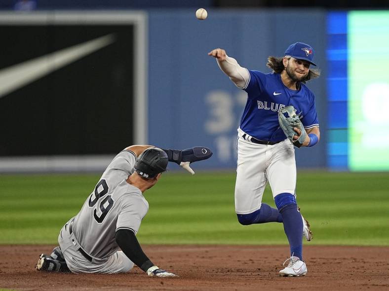 Sep 26, 2022; Toronto, Ontario, CAN; Toronto Blue Jays shortstop Bo Bichette (right) throws to first base after forcing New York Yankees right fielder Aaron Judge (99) out at second base during the third inning at Rogers Centre. Mandatory Credit: John E. Sokolowski-USA TODAY Sports