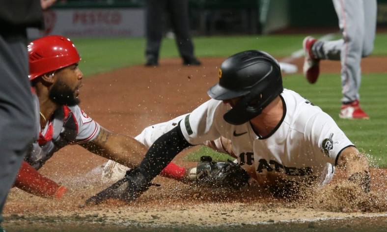Sep 26, 2022; Pittsburgh, Pennsylvania, USA; Pittsburgh Pirates second baseman Kevin Newman (right) slides across home plate to score a run ahead of the tag by Cincinnati Reds catcher Chuckie Robinson (left) during the fifth inning at PNC Park. Mandatory Credit: Charles LeClaire-USA TODAY Sports