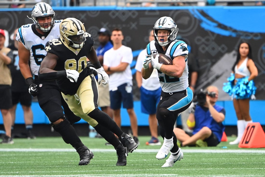 Sep 25, 2022; Charlotte, North Carolina, USA; Carolina Panthers running back Christian McCaffrey (22) with the ball as New Orleans Saints defensive end Tanoh Kpassagnon (90) defends in the fourth quarter at Bank of America Stadium. Mandatory Credit: Bob Donnan-USA TODAY Sports