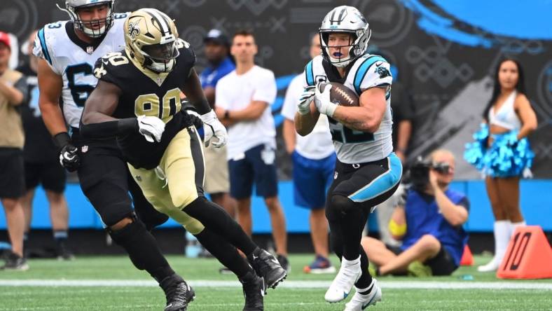 Sep 25, 2022; Charlotte, North Carolina, USA; Carolina Panthers running back Christian McCaffrey (22) with the ball as New Orleans Saints defensive end Tanoh Kpassagnon (90) defends in the fourth quarter at Bank of America Stadium. Mandatory Credit: Bob Donnan-USA TODAY Sports