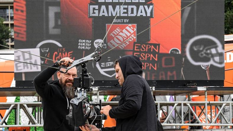 ESPN staff cover a video camera to protect from Hurricane Ian rain, on the ESPN College GameDay Built by The Home Depot set on Bowman Field at Clemson University in Clemson Friday, September 30, 2022. The show's 427th road show, the eighth at Clemson before the game with NC State, airs on television from 9 a.m. to noon Eastern time.

Espn College Gameday On Bowman Field At Clemson