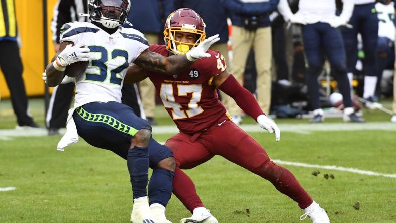 Dec 20, 2020; Landover, Maryland, USA; Washington Football Team linebacker Khaleke Hudson (47) tackles Seattle Seahawks running back Chris Carson (32) during the second half at FedExField. Mandatory Credit: Brad Mills-USA TODAY Sports