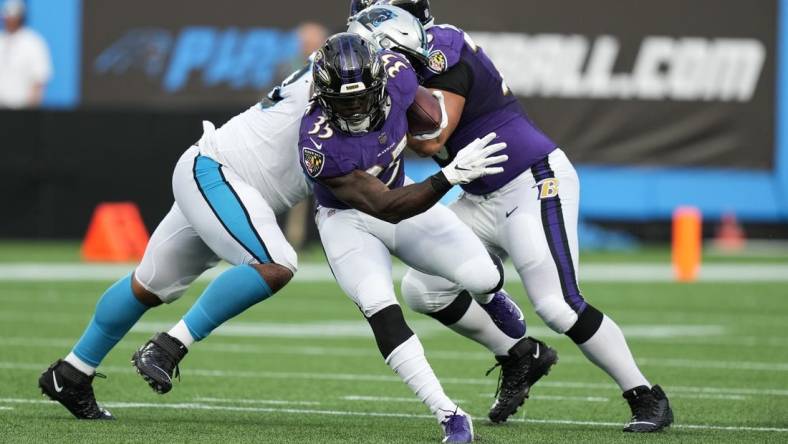 Aug 21, 2021; Charlotte, North Carolina, USA; Baltimore Ravens running back Gus Edwards (35) eludes a tackle by the Carolina Panthers defense for yardage during the first quarter at Bank of America Stadium. Mandatory Credit: Jim Dedmon-USA TODAY Sports